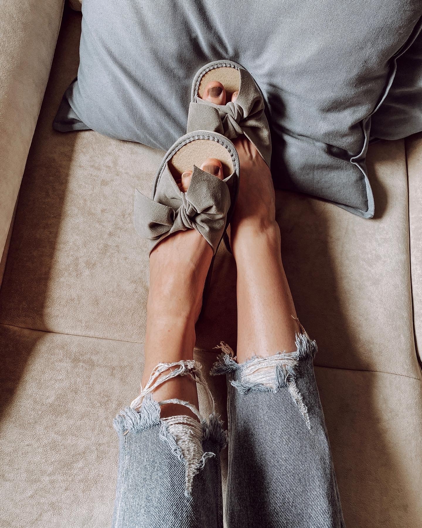 Stylish grey suede slippers with a decorative ribbon front and cushioned insole, perfect for home wear.