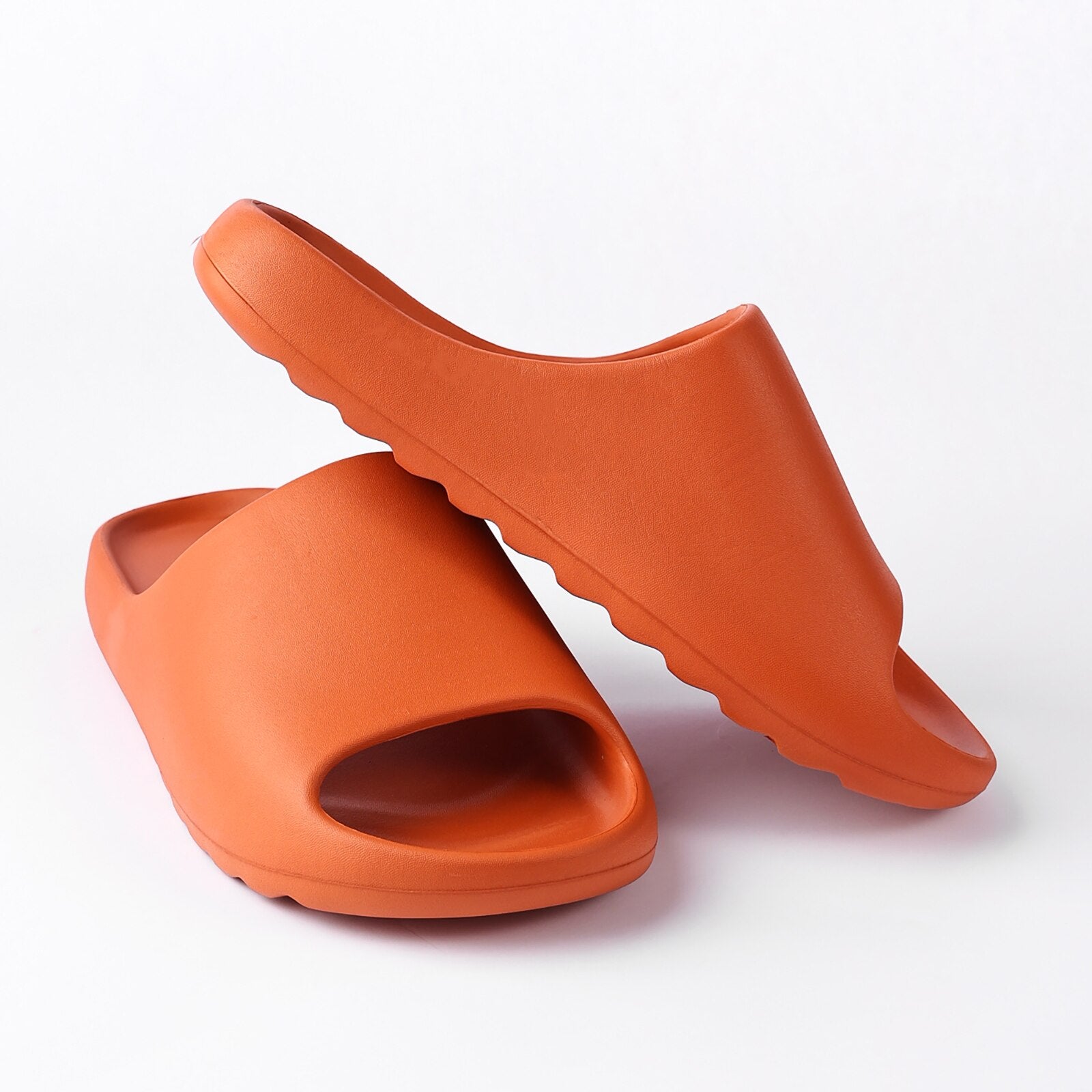 A pair of orange chunky platform pillow slides for women, featuring an open toe design and a cushioned insole, perfect for casual wear and shower use.