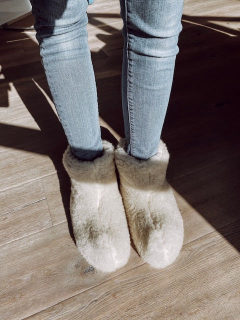 A pair of elegant white boots made from natural sheep wool, showcasing a cozy interior and durable rubber sole, perfect for stylish comfort.