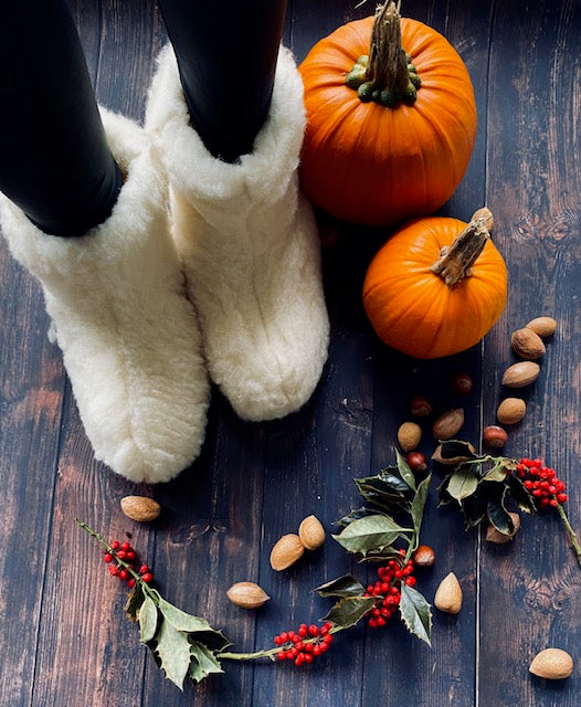 A pair of elegant white boots made from natural sheep wool, showcasing a cozy interior and durable rubber sole, perfect for stylish comfort.