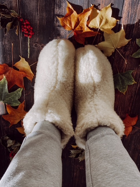 A pair of elegant white boots made from natural sheep wool, showcasing a cozy interior and durable rubber sole, perfect for stylish comfort.