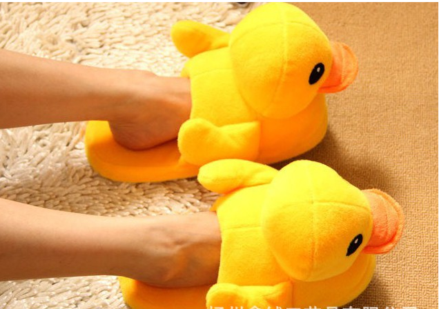 A pair of cute yellow duck slippers designed for women, featuring soft plush material and a whimsical design, perfect for indoor winter wear.