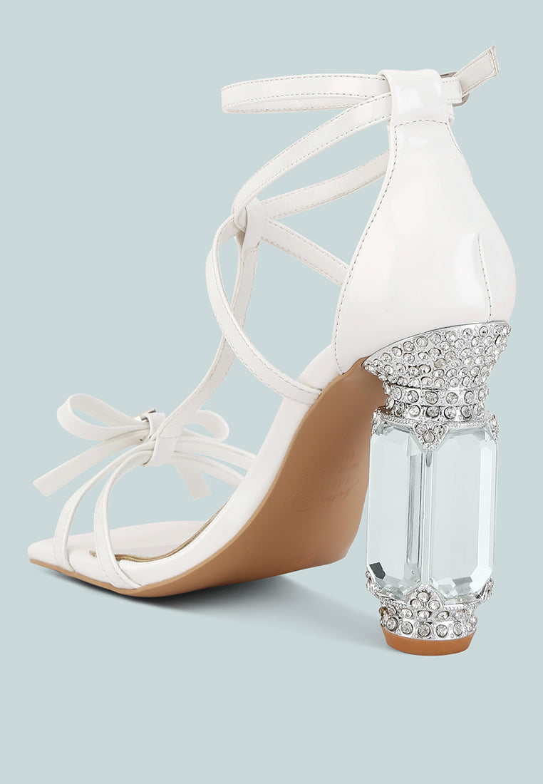 Affluence Jeweled High Heel Sandals featuring embellished bow, fantasy heel, and ankle strap for stylish summer wear.