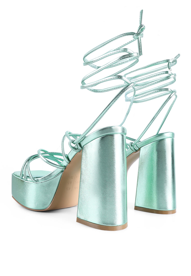 Anvil Metallic Block Heeled Lace Up Sandals featuring a shiny metallic faux leather upper, open square toe, and trendy lace-up design.