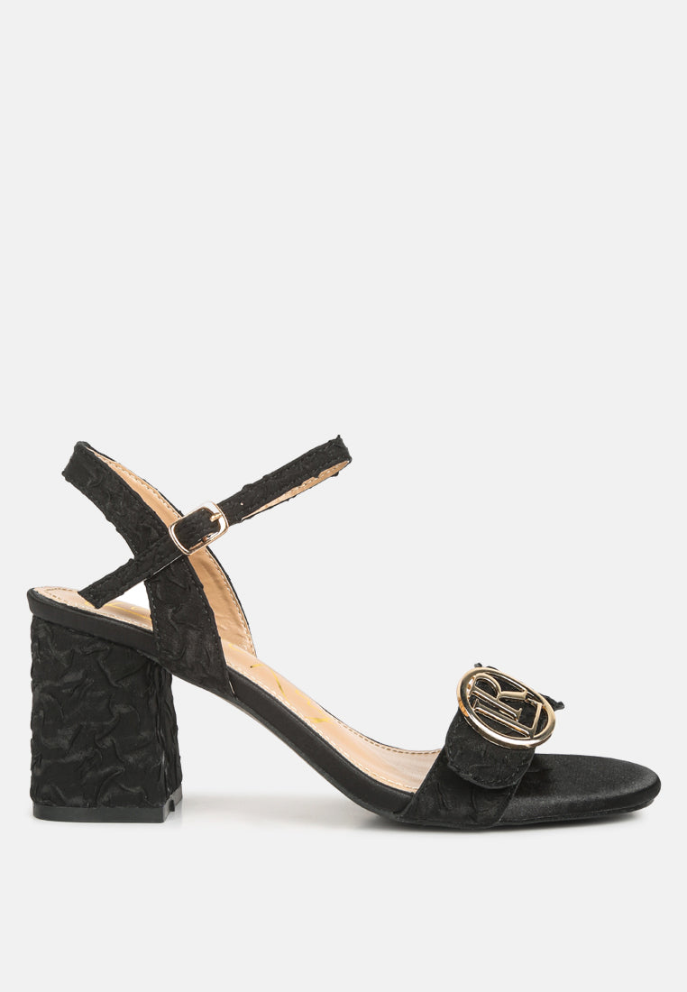 Chaplet Textured Block Heel Sandals featuring a satin upper, block heel, and pin buckle closure, perfect for stylish comfort.