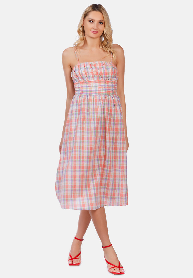 A stylish checkered midi slip dress with tie-up straps and a wrapped waist, made from 100% cotton, perfect for casual outings.