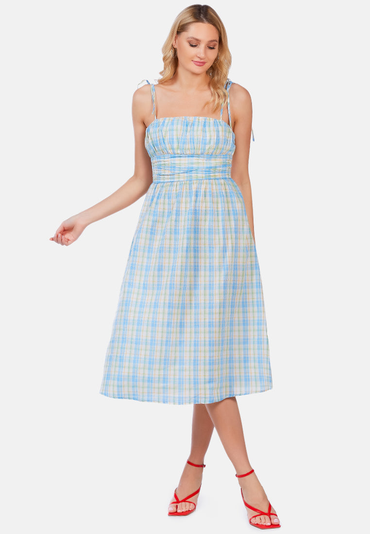 A stylish checkered midi slip dress with tie-up straps and a wrapped waist, made from 100% cotton, perfect for casual outings.