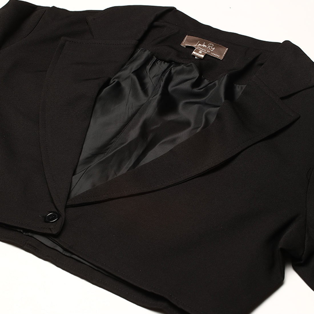 A stylish cropped tailored blazer featuring lapels and button detailing, made from a soft polyester-spandex blend.