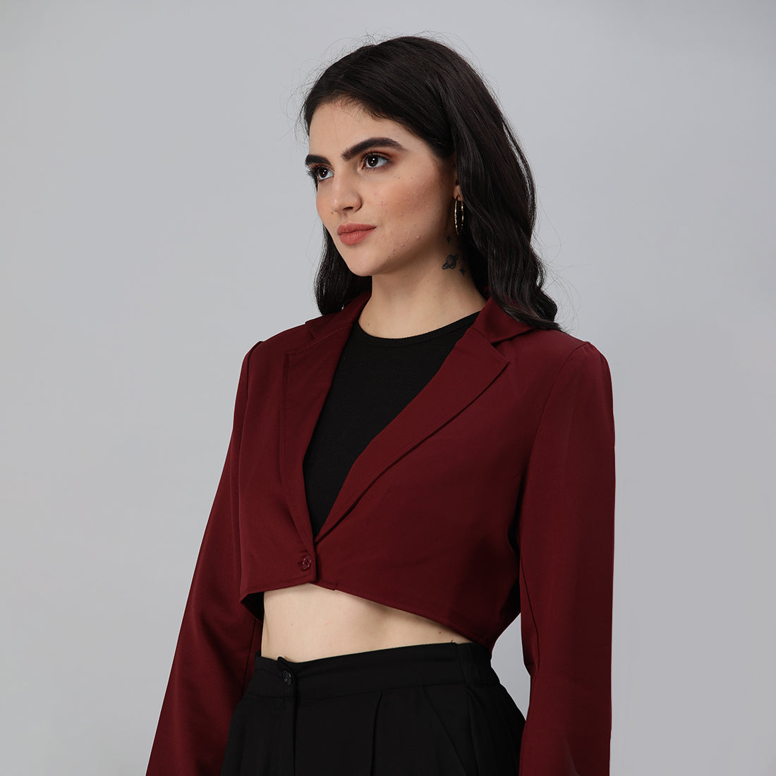 A stylish cropped tailored blazer featuring lapels and button detailing, made from a soft polyester-spandex blend.