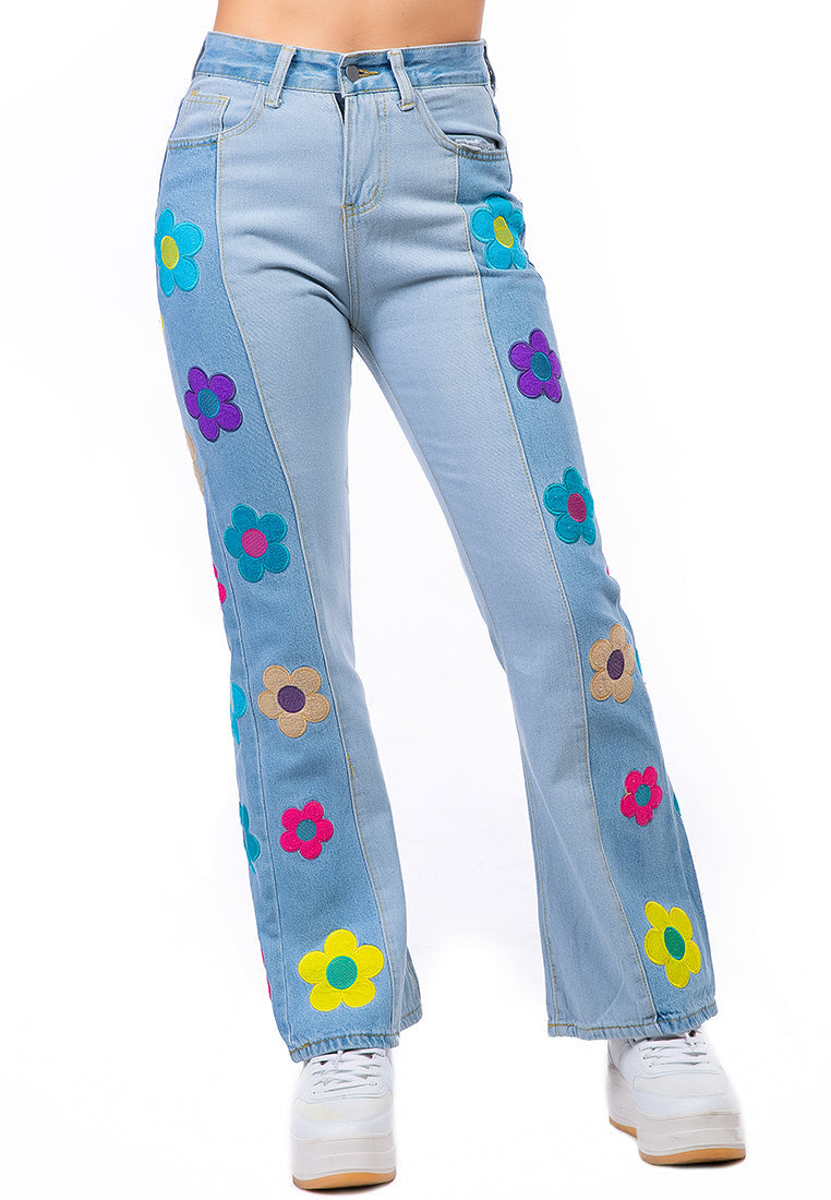 A pair of women's boot-cut jeans featuring embroidered daisy patterns on a washed denim fabric, showcasing a relaxed fit and multiple pockets.