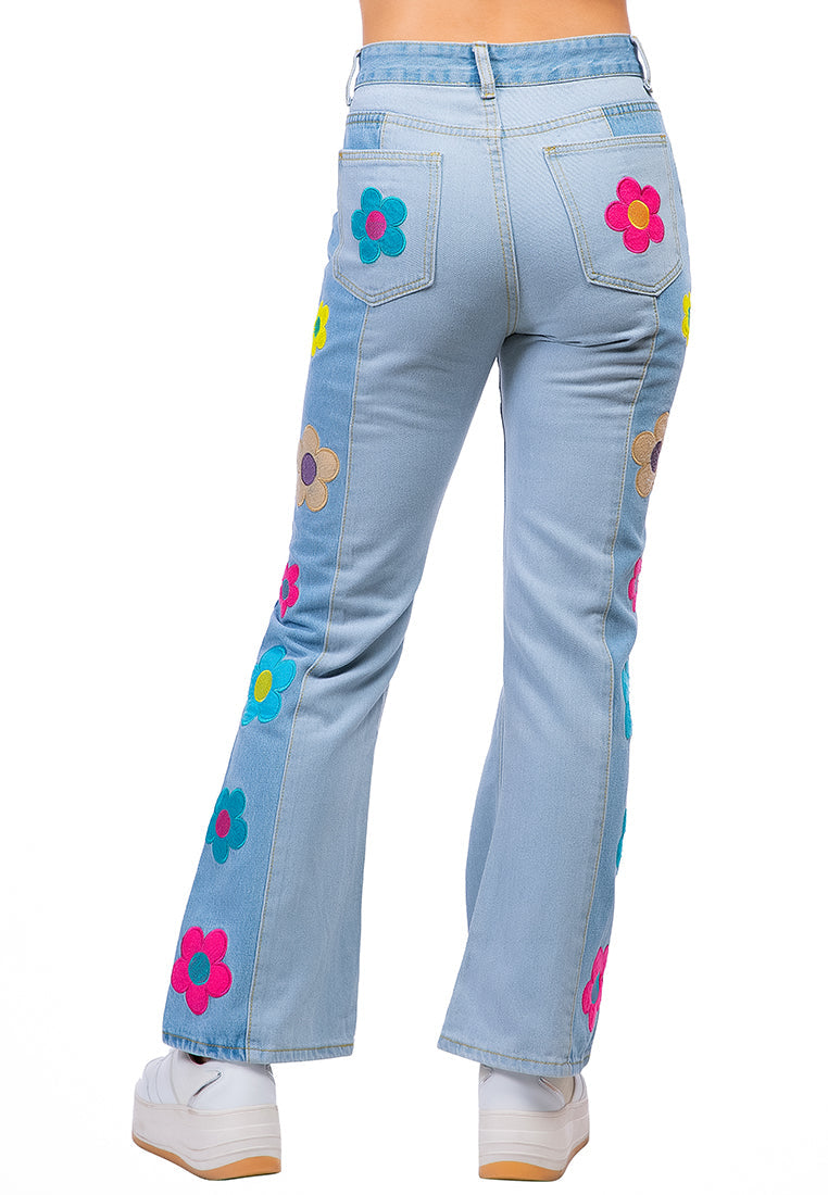 A pair of women's boot-cut jeans featuring embroidered daisy patterns on a washed denim fabric, showcasing a relaxed fit and multiple pockets.