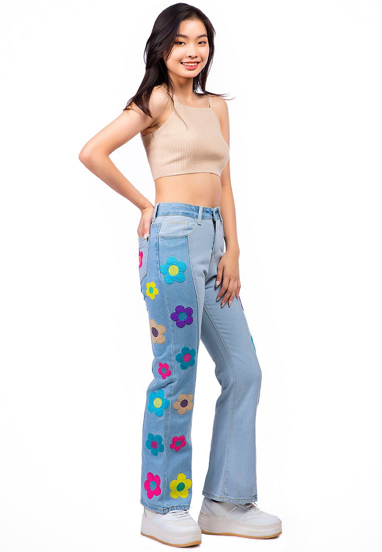 A pair of women's boot-cut jeans featuring embroidered daisy patterns on a washed denim fabric, showcasing a relaxed fit and multiple pockets.