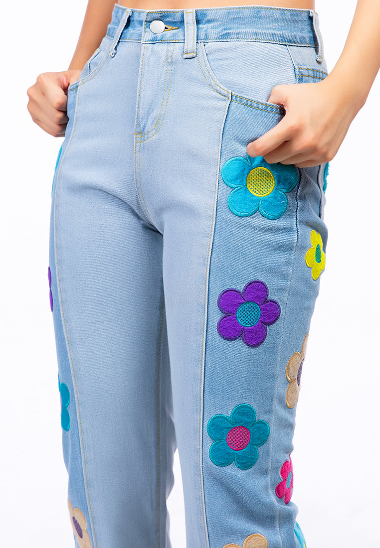 A pair of women's boot-cut jeans featuring embroidered daisy patterns on a washed denim fabric, showcasing a relaxed fit and multiple pockets.