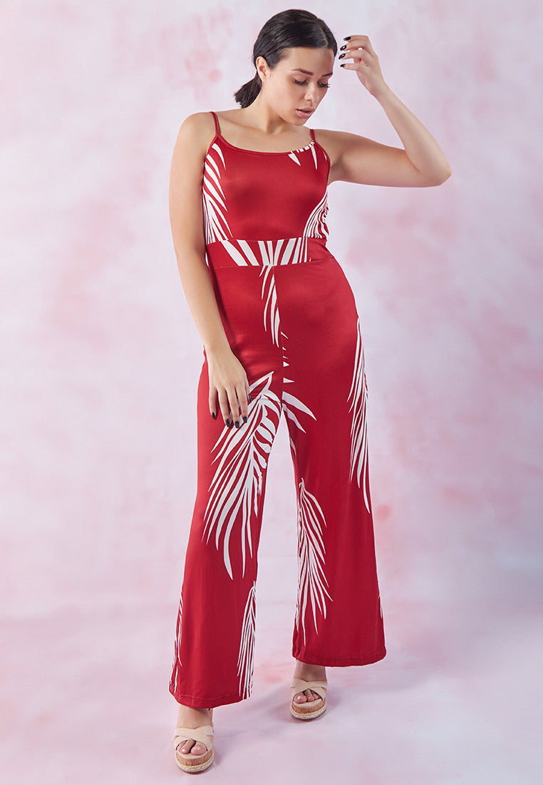 A stylish spaghetti strap jumpsuit featuring a white palm leaves print, perfect for beach outings and summer events.