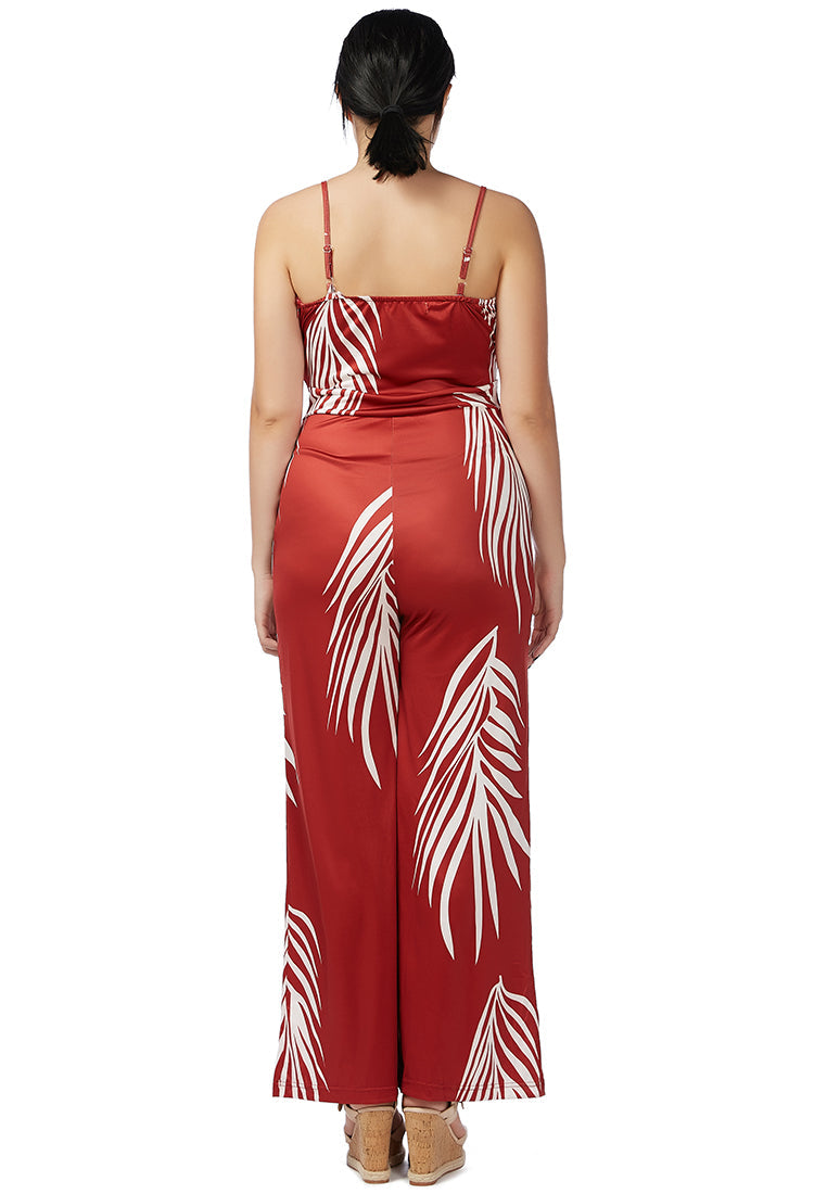 A stylish spaghetti strap jumpsuit featuring a white palm leaves print, perfect for beach outings and summer events.