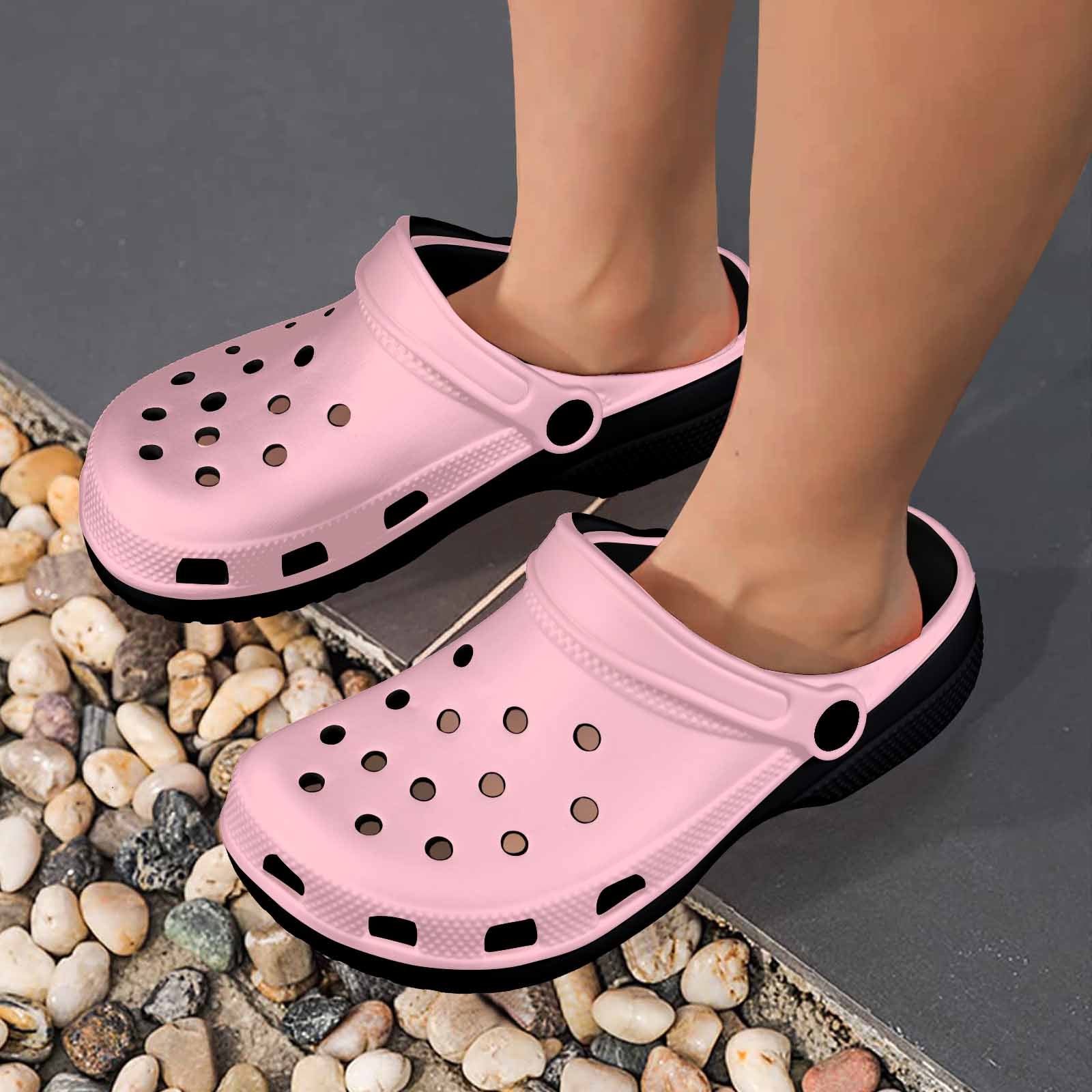 A pair of pink adult clogs made from lightweight EVA material, featuring ventilation ports and pivoting heel straps for a secure fit.