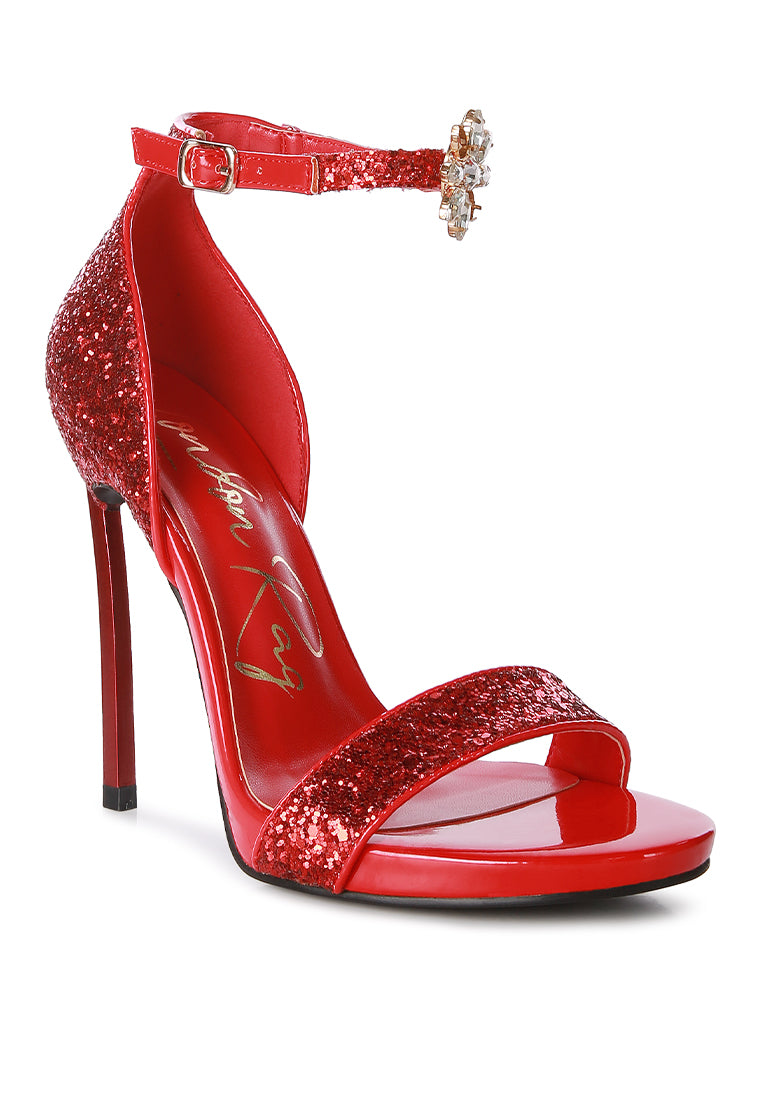 A pair of glamorous Straight Fire High Heel Glitter Stilettos featuring a glittery finish, floral jewel brooch, and a secure ankle strap.