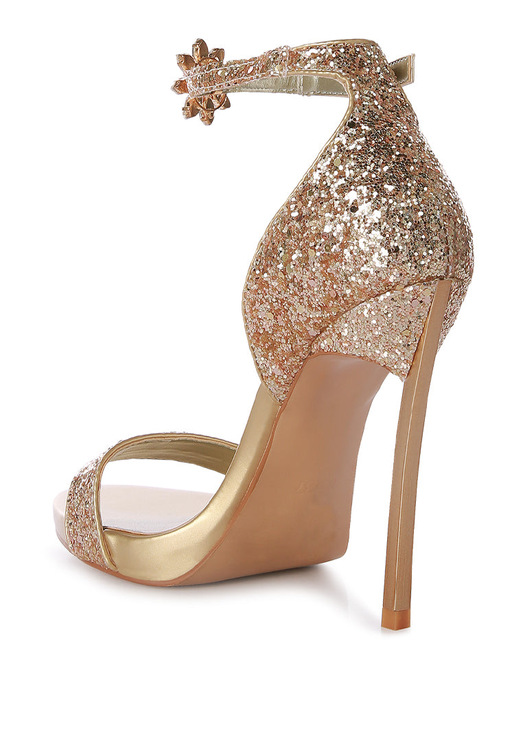 A pair of glamorous Straight Fire High Heel Glitter Stilettos featuring a glittery finish, floral jewel brooch, and a secure ankle strap.