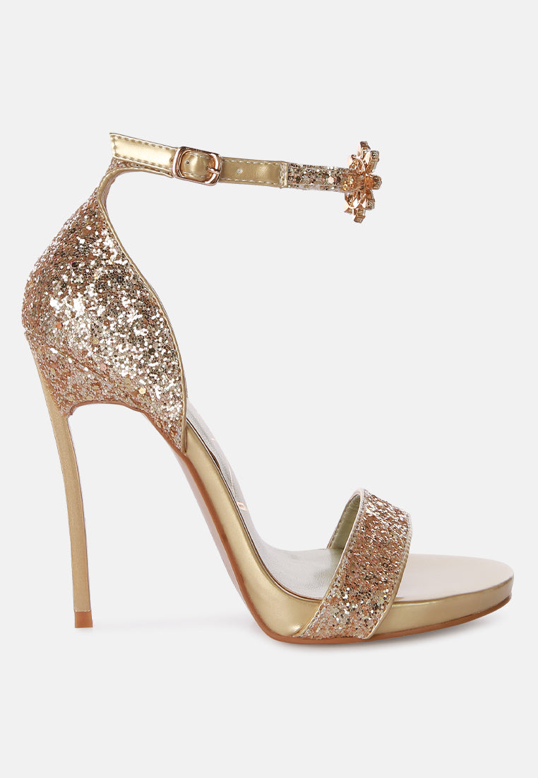 A pair of glamorous Straight Fire High Heel Glitter Stilettos featuring a glittery finish, floral jewel brooch, and a secure ankle strap.