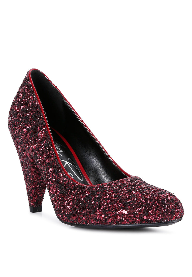 A pair of Sugar Plum Glitter Conical Heel Pumps showcasing a sparkling glitter exterior, conical heels, and a closed toe design, perfect for evening wear.