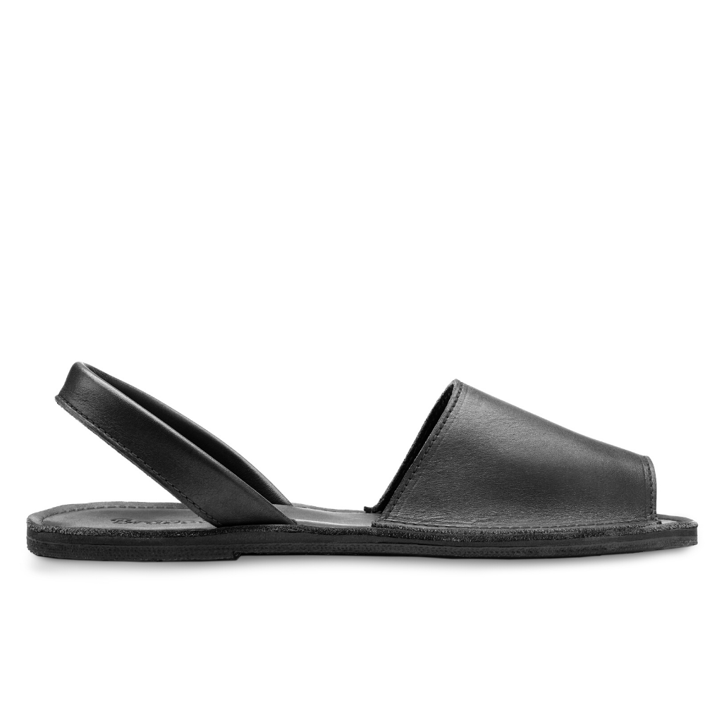 The Avarca women's flat leather sandal in black, showcasing its minimalist design and strappy heel.