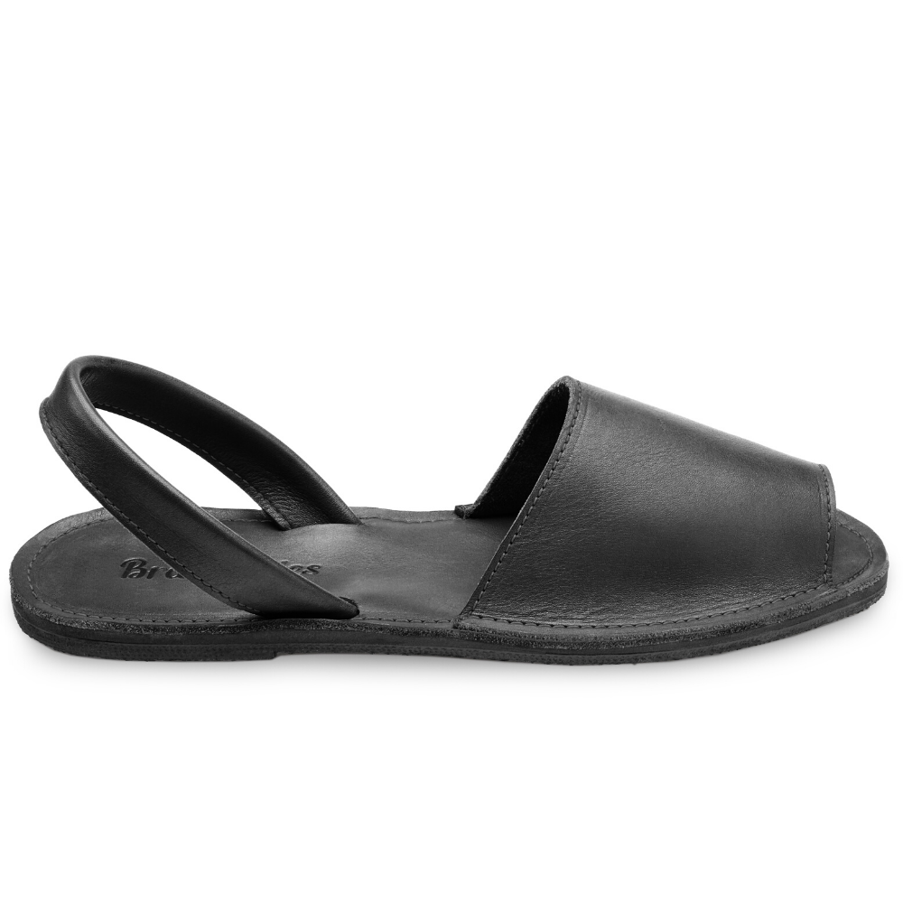 The Avarca women's flat leather sandal in black, showcasing its minimalist design and strappy heel.