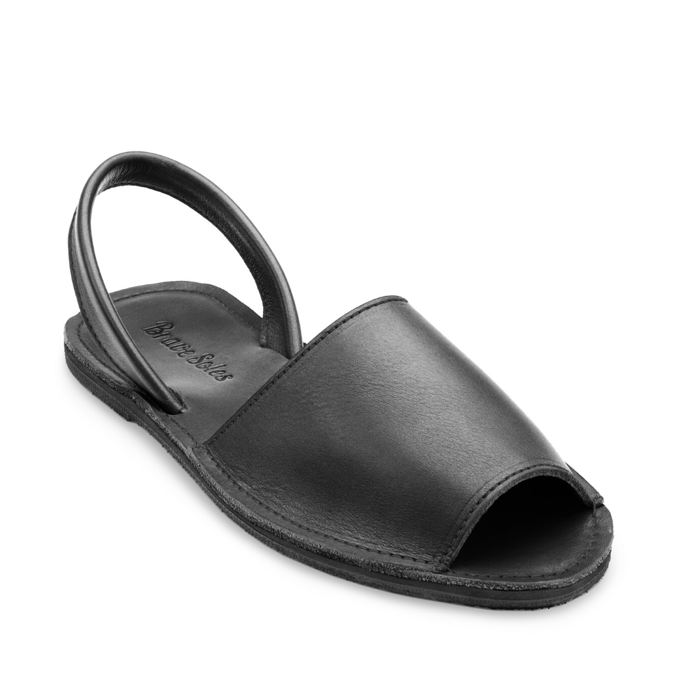 The Avarca women's flat leather sandal in black, showcasing its minimalist design and strappy heel.