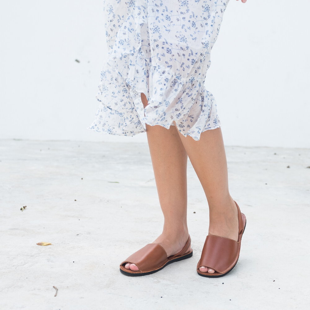 The Avarca women's flat leather sandal in black, showcasing its minimalist design and strappy heel.