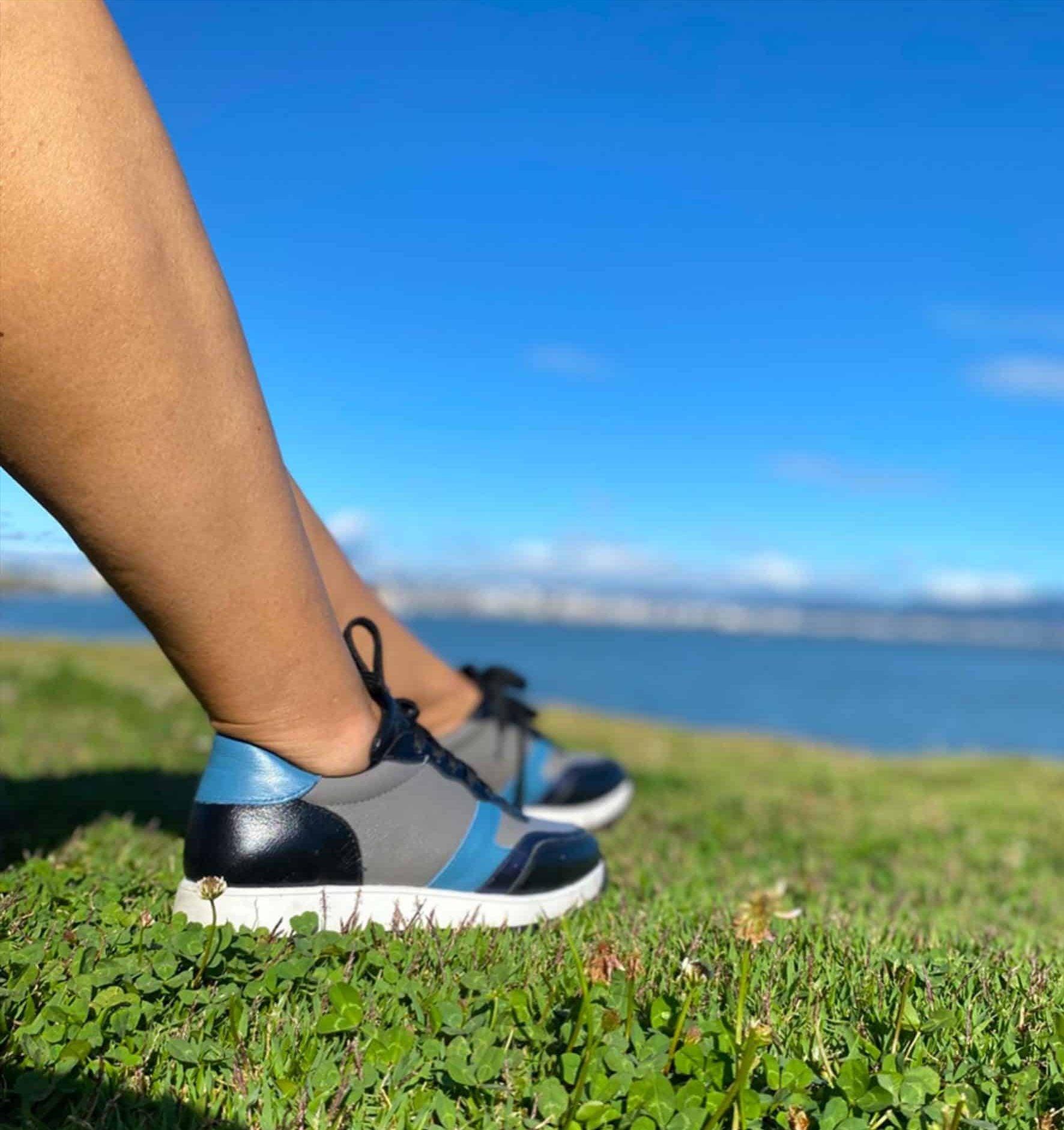 Stylish Mangará Buriri Walking Women's Sneakers in polished leather with grey, blue, and black accents, featuring a low-top silhouette and lace-up design.