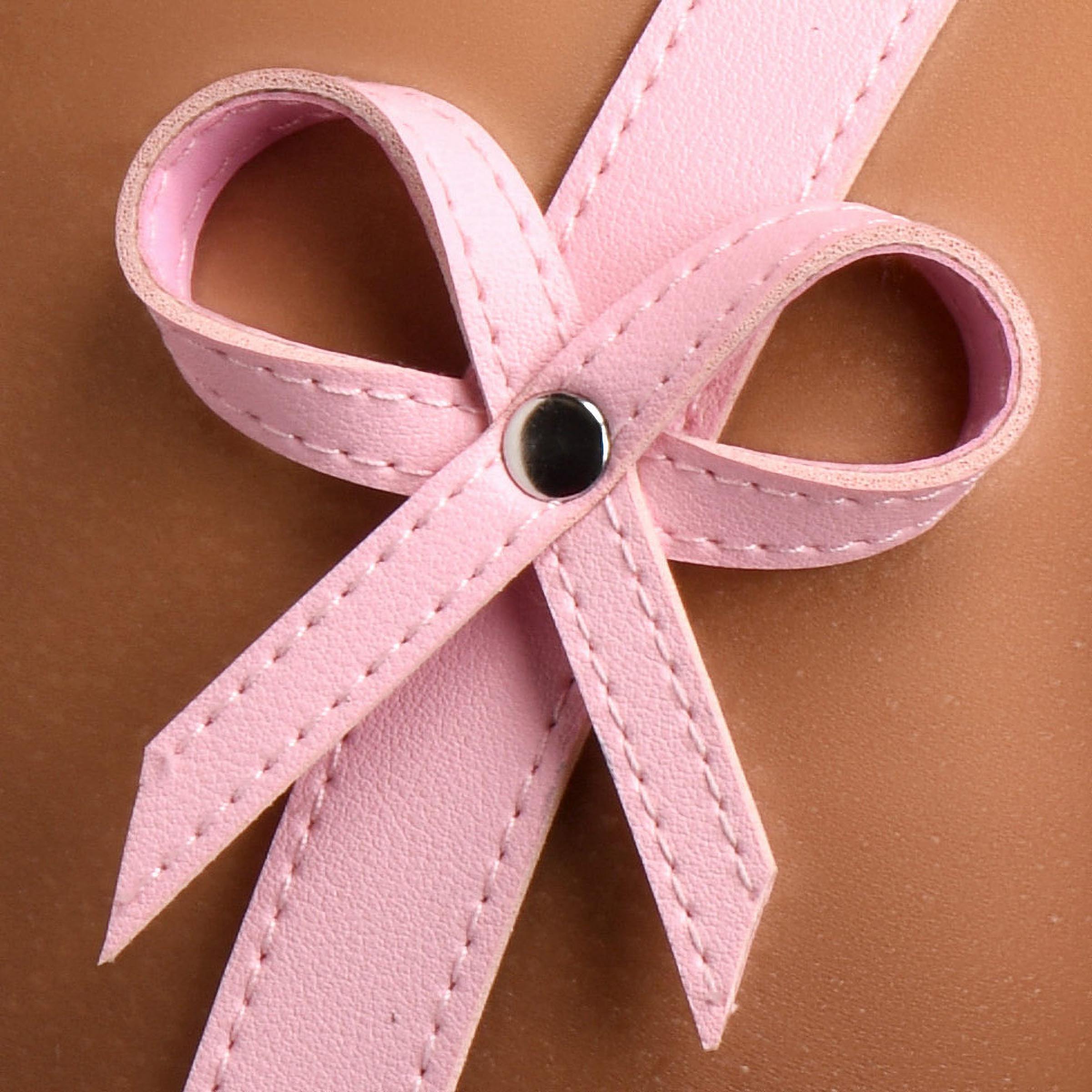 Pink bondage harness with bows, adjustable straps, and nickel-free metal buckles, designed for comfort and style.