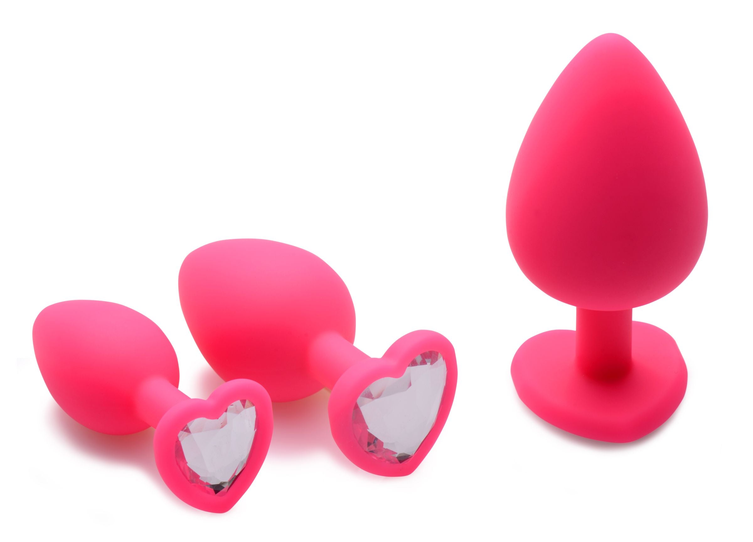 A set of three pink silicone anal plugs with heart-shaped gem accents, showcasing graduated sizes for beginners.