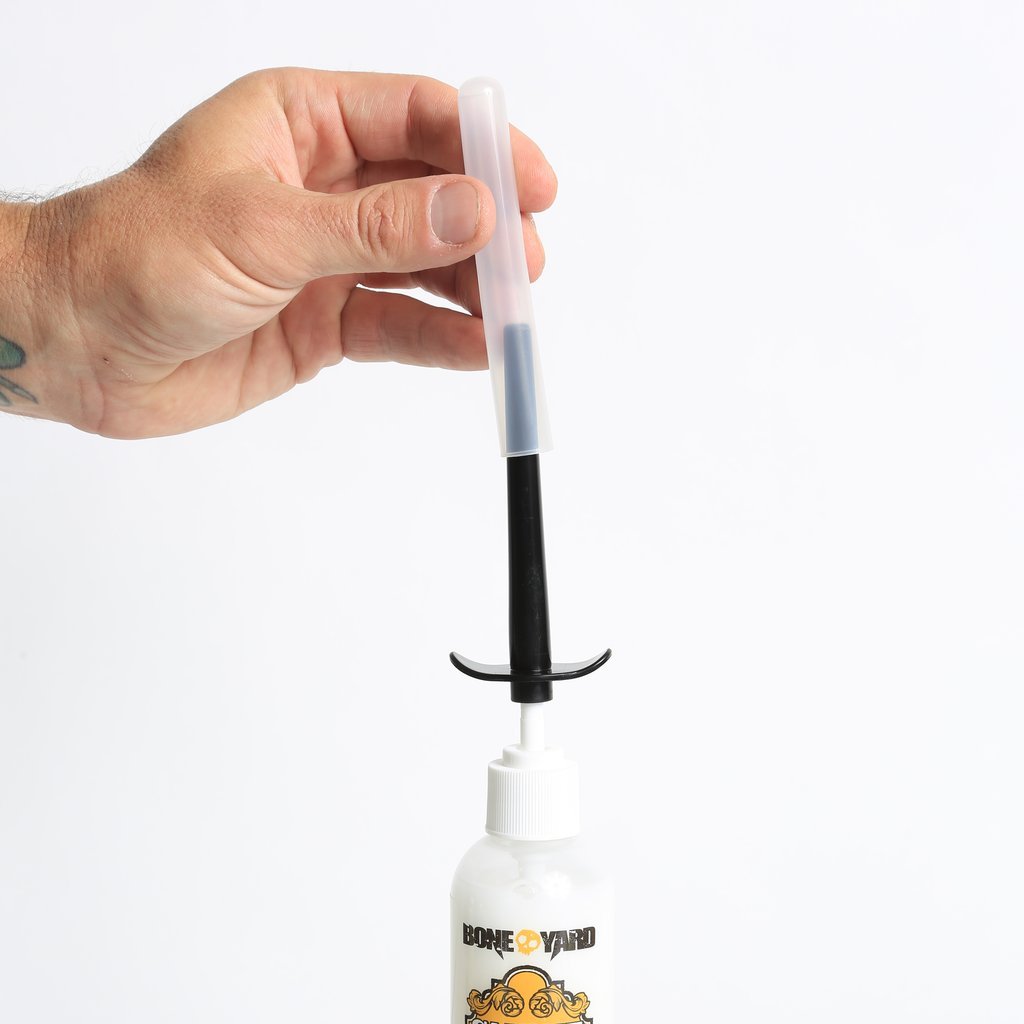 The Skwert Lube Injector with a 4-inch nozzle, small and large bottle caps, and a sanitary storage cap, designed for easy and precise lubrication.