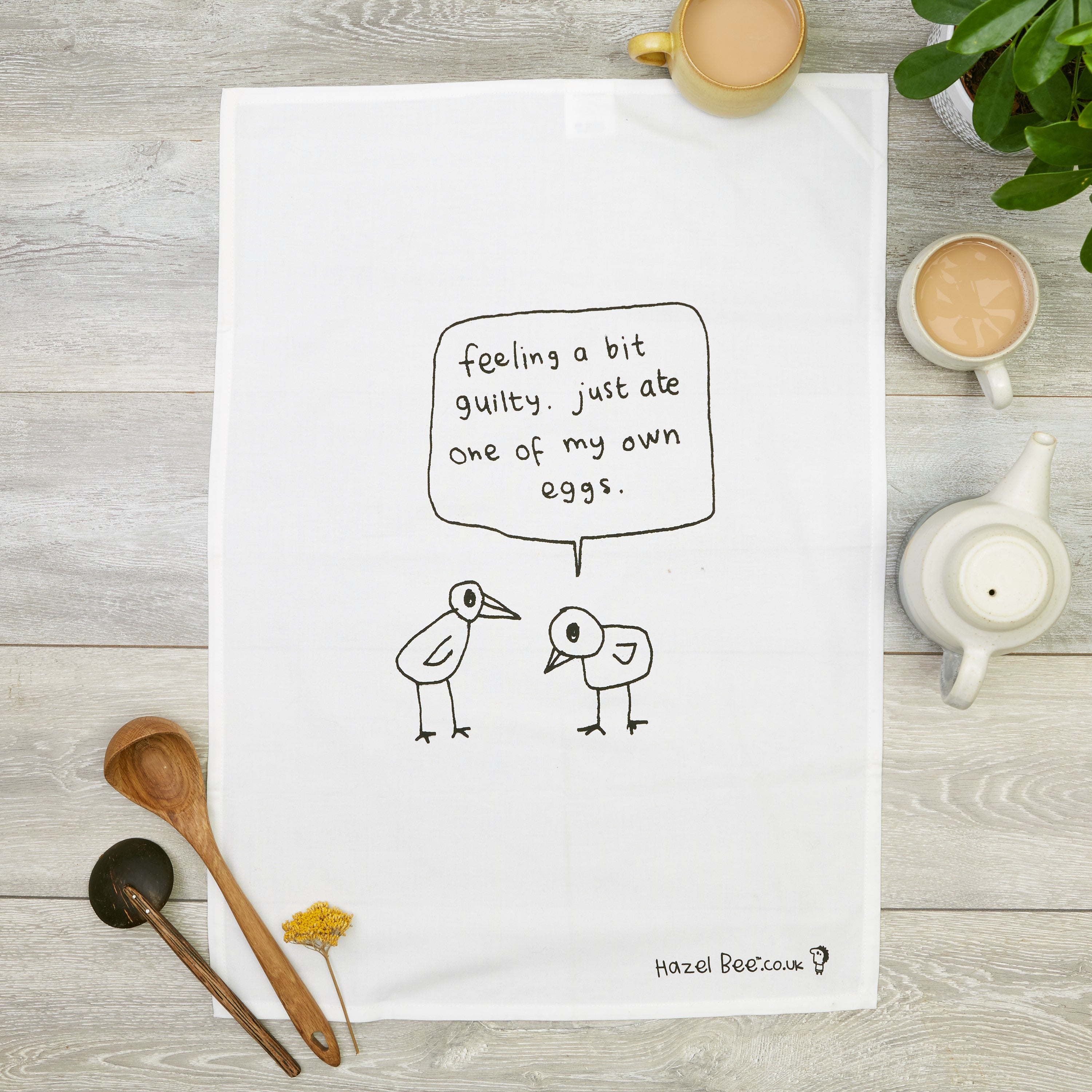 Ate My Own Egg Tea Towel made from organic cotton, featuring a playful design in black ink, with a hanging loop for easy storage.