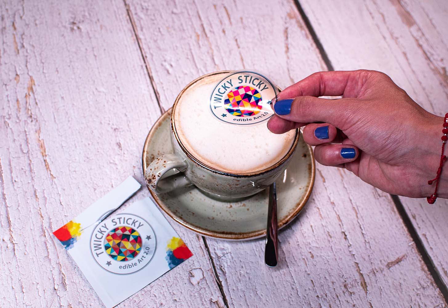 Hand placing edible sticker on latte.