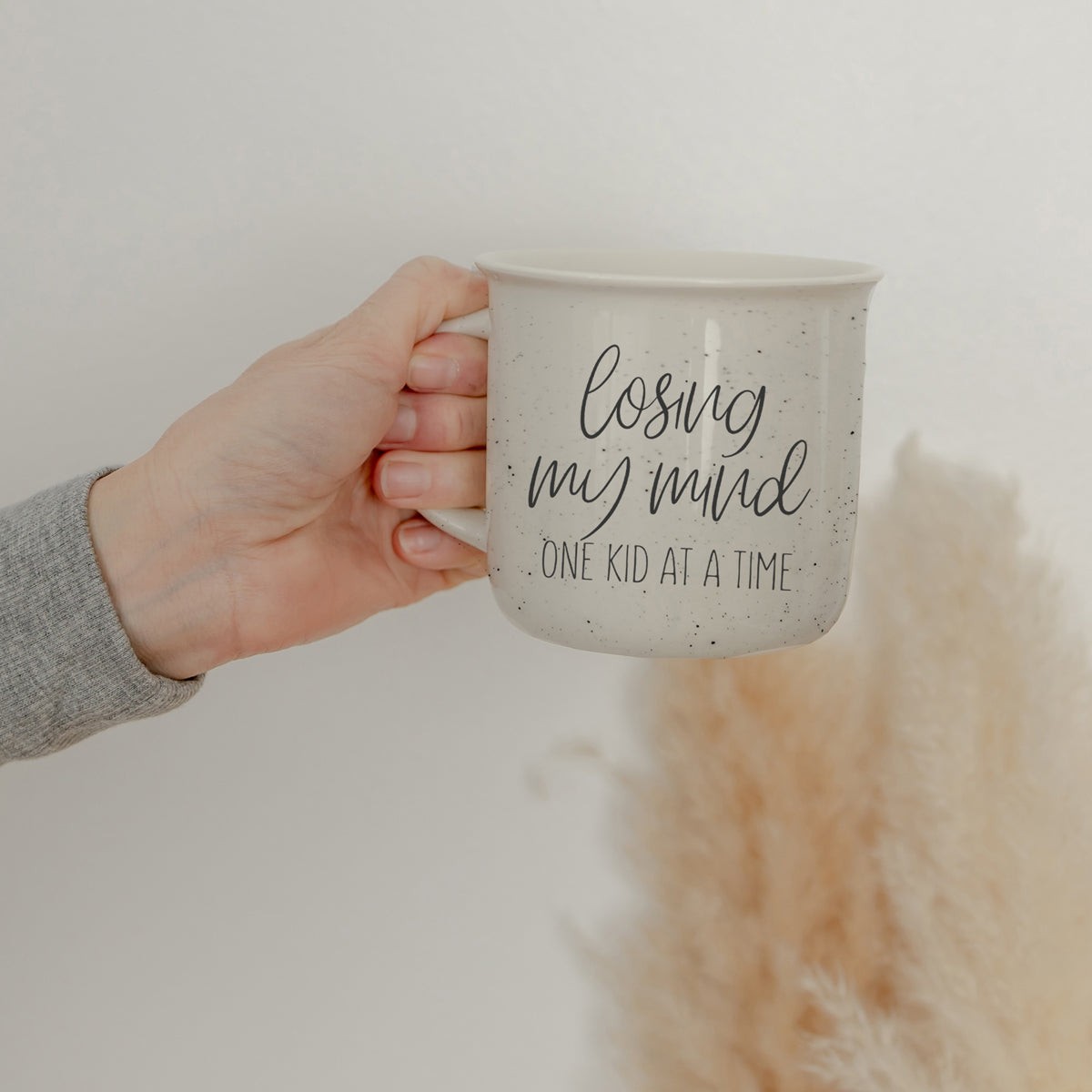 A 14.5oz ceramic campfire style coffee mug with a humorous quote for parents, featuring a light ivory color with speckles and black lettering.