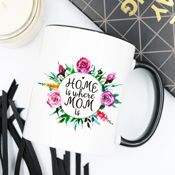 White 11oz coffee mug with funny design 'Home Is Where Mom Is' printed on both sides, showcasing high-quality ceramic material.