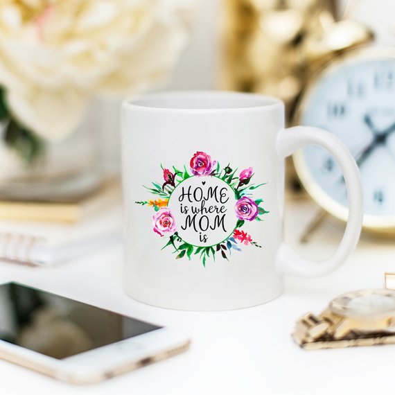 White 11oz coffee mug with funny design 'Home Is Where Mom Is' printed on both sides, showcasing high-quality ceramic material.