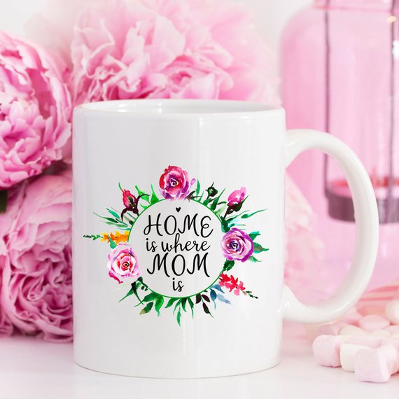 White 11oz coffee mug with funny design 'Home Is Where Mom Is' printed on both sides, showcasing high-quality ceramic material.