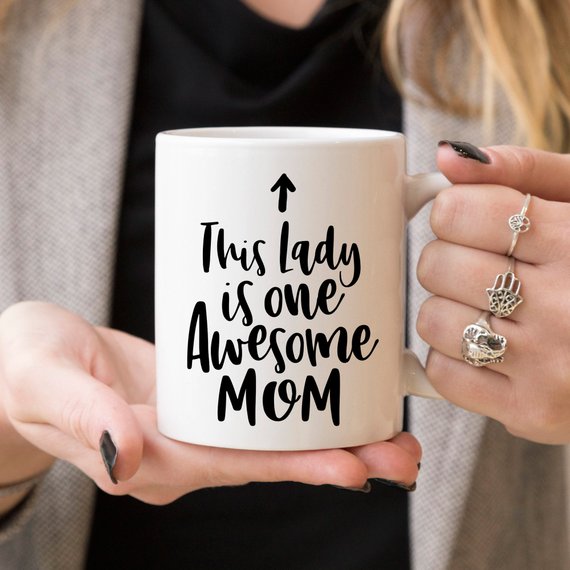 A humorous 11oz coffee mug featuring the phrase 'This Lady Is One Awesome Mom' with a stylish design, perfect for gifting.