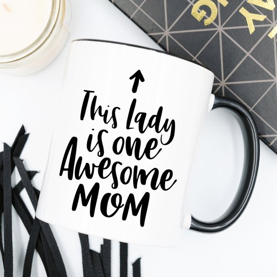 A humorous 11oz coffee mug featuring the phrase 'This Lady Is One Awesome Mom' with a stylish design, perfect for gifting.