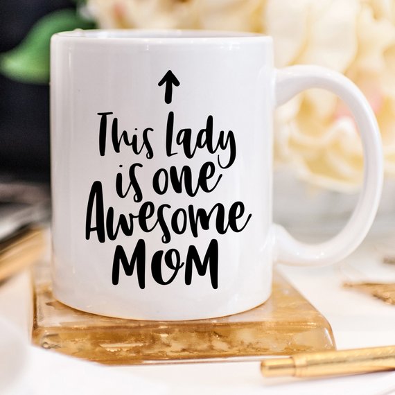 A humorous 11oz coffee mug featuring the phrase 'This Lady Is One Awesome Mom' with a stylish design, perfect for gifting.