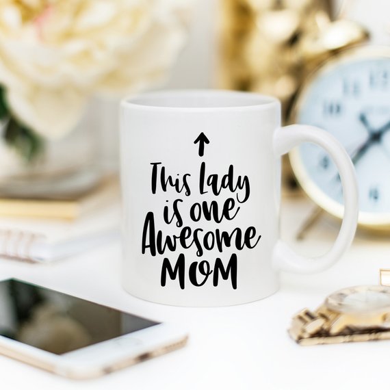 A humorous 11oz coffee mug featuring the phrase 'This Lady Is One Awesome Mom' with a stylish design, perfect for gifting.