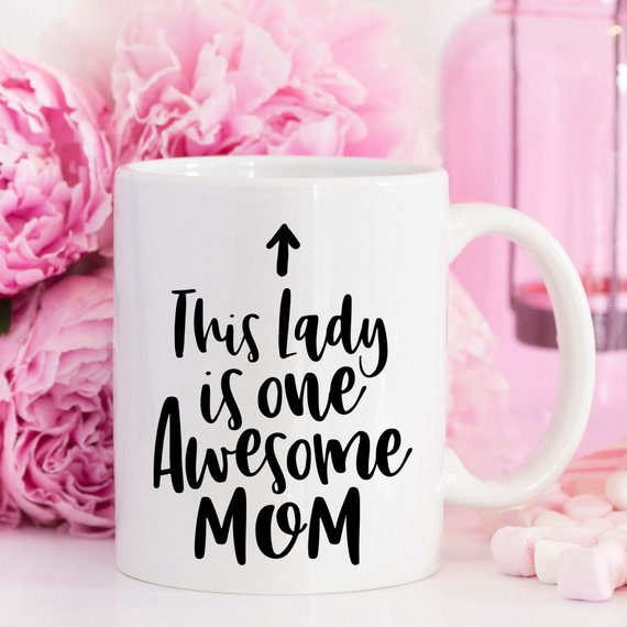 A humorous 11oz coffee mug featuring the phrase 'This Lady Is One Awesome Mom' with a stylish design, perfect for gifting.