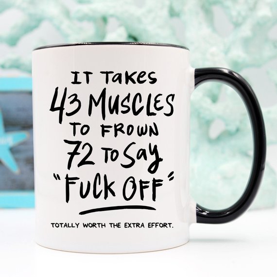 A humorous coffee mug featuring the phrase 'It Takes 43 Muscles To Frown, 72 To Say 'Fuck Off'.' Perfect for coffee lovers.