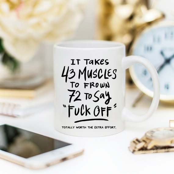 A humorous coffee mug featuring the phrase 'It Takes 43 Muscles To Frown, 72 To Say 'Fuck Off'.' Perfect for coffee lovers.