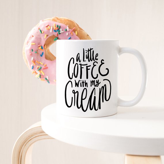 A humorous coffee mug with the phrase 'A Little Coffee With My Cream' printed on it, showcasing a fun design perfect for coffee lovers.