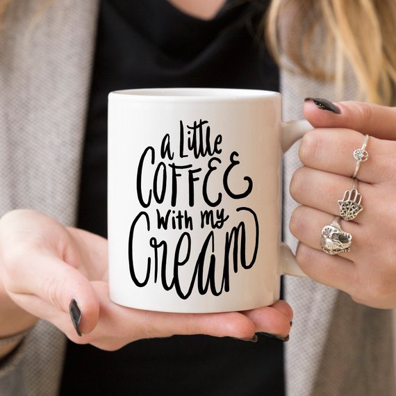 A humorous coffee mug with the phrase 'A Little Coffee With My Cream' printed on it, showcasing a fun design perfect for coffee lovers.