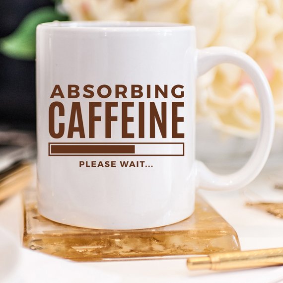 A humorous coffee mug with the phrase 'Absorbing Caffeine Please Wait', showcasing a fun design perfect for Mother's Day gifts.