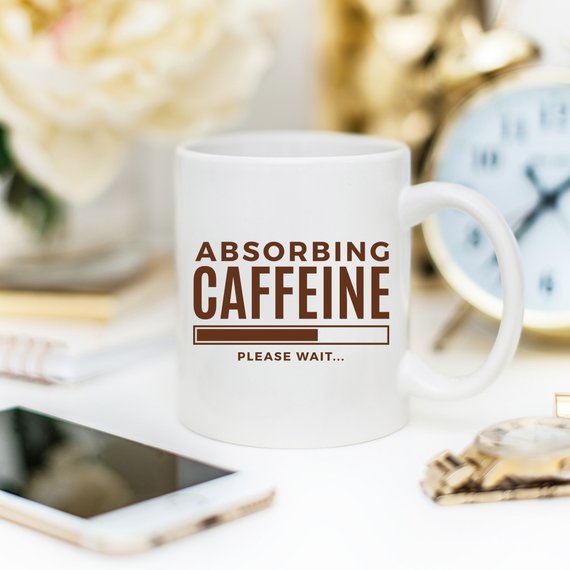 A humorous coffee mug with the phrase 'Absorbing Caffeine Please Wait', showcasing a fun design perfect for Mother's Day gifts.