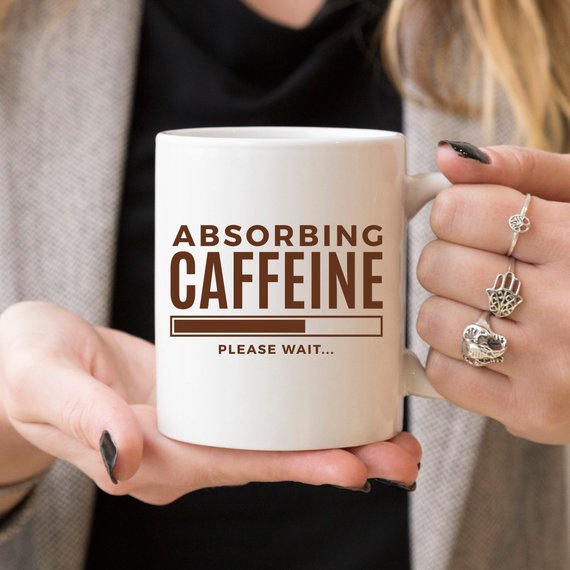 A humorous coffee mug with the phrase 'Absorbing Caffeine Please Wait', showcasing a fun design perfect for Mother's Day gifts.